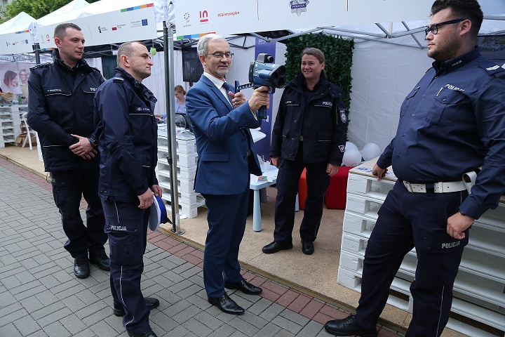 Minister Kwieciński stoi z czterema policjantami w ręku trzyma miernik prędkości