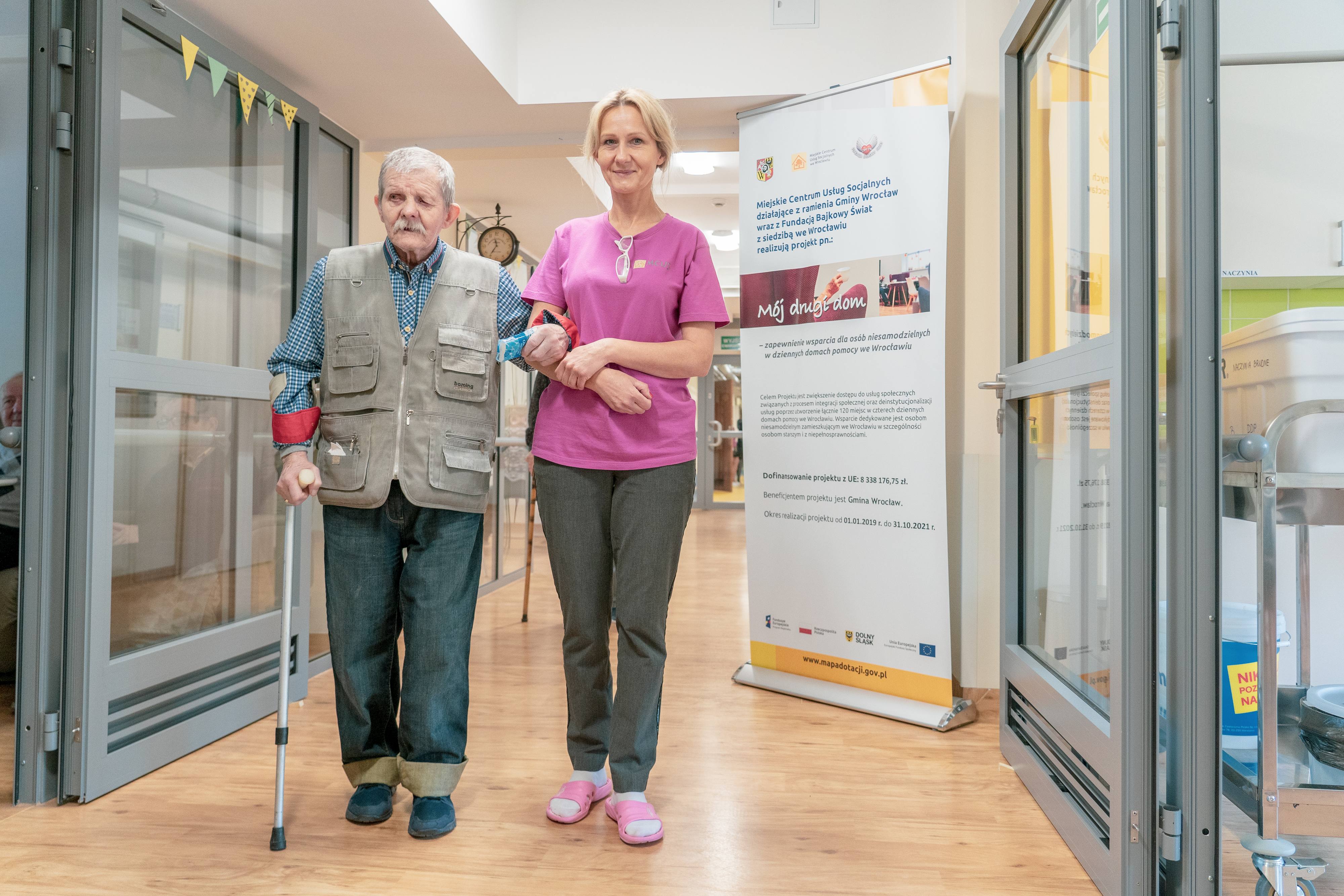 An elderly man walking along the corridor with a nurse in a social welfare home in Wroclaw.