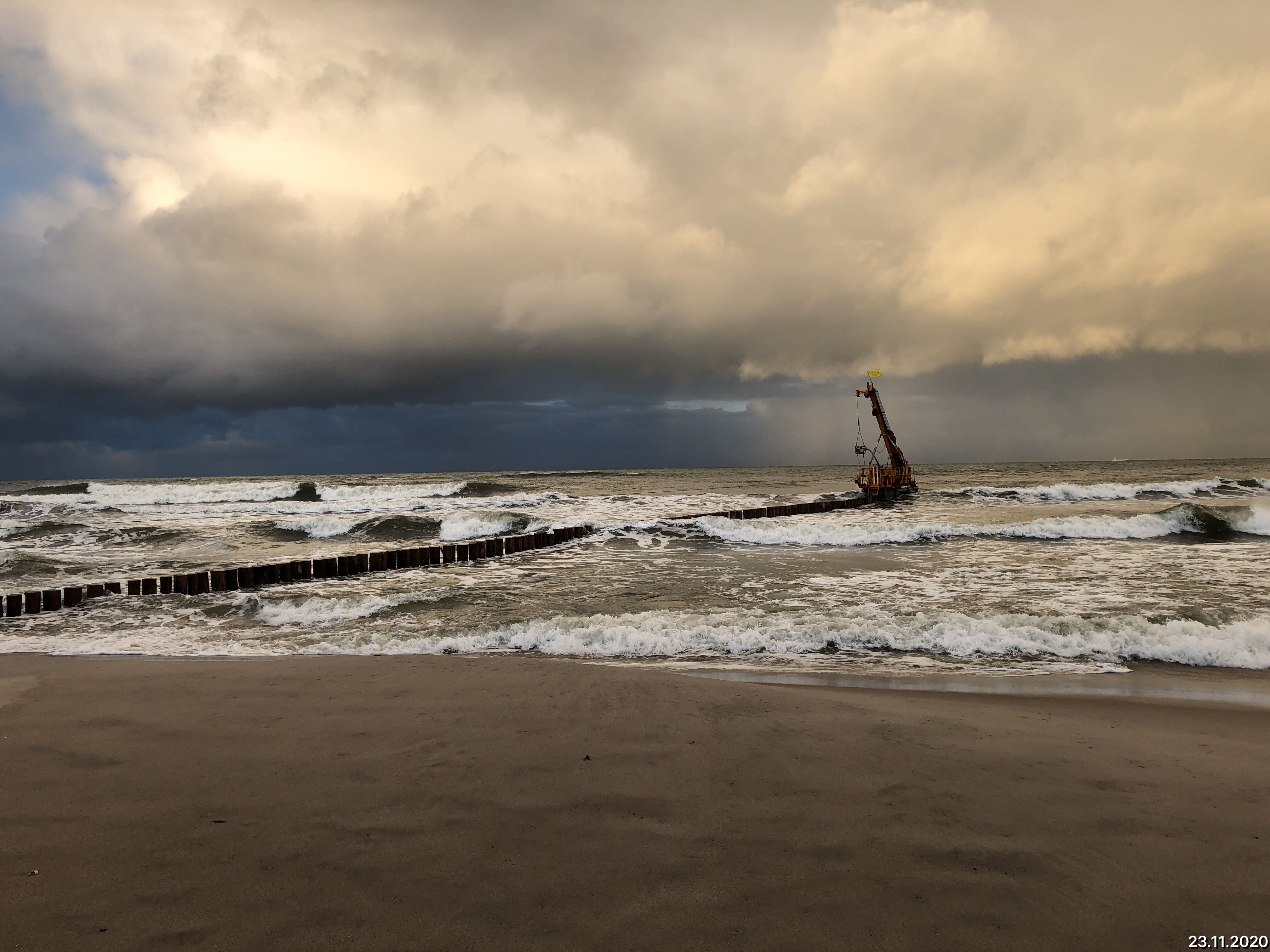 Wzburzone morze w oddali maszyna wbijająca drewniane słupy