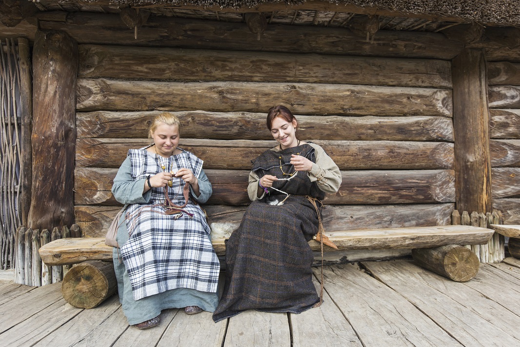 Kobiety w kostiumie historycznym na ławce przed chatą skansenu