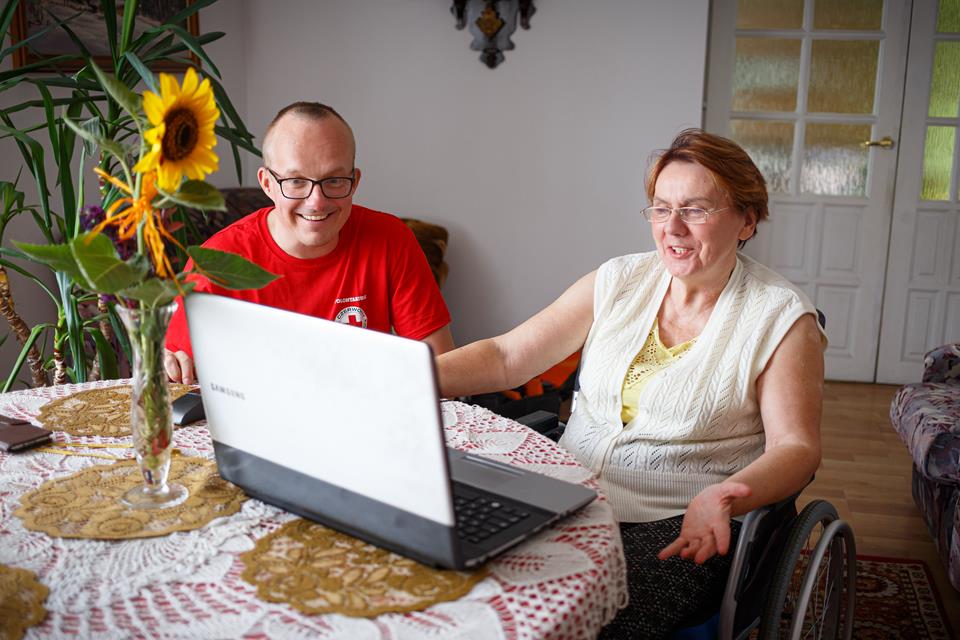 Senior with a caregiver at a table with a laptop
