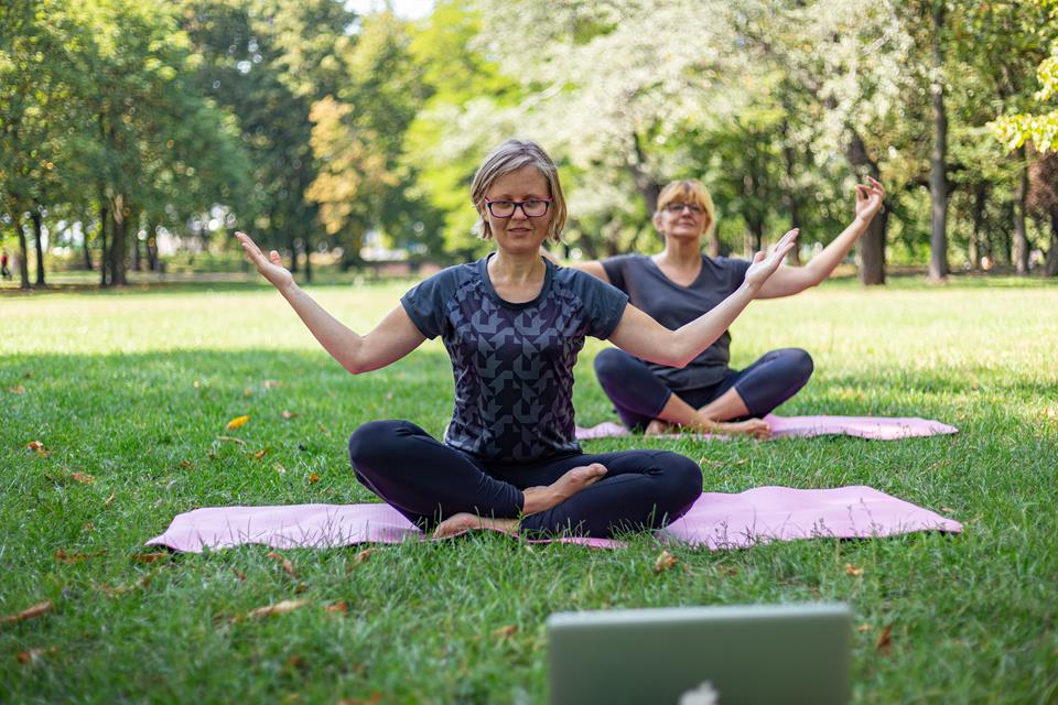 Two women practice yoga in a park