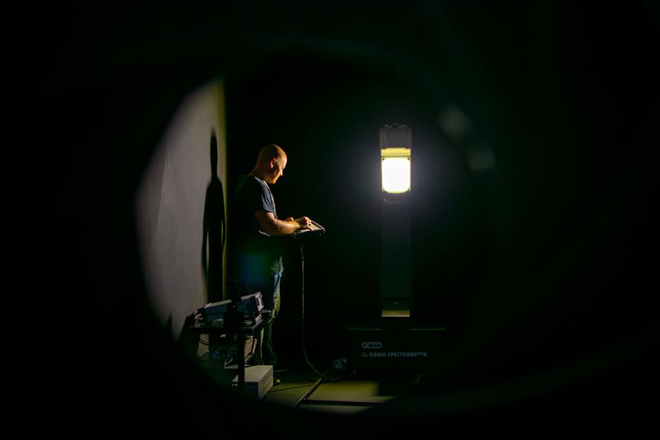 Man examines lamp fitting in photometric darkroom